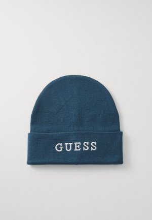 Beanie lavorato a maglia di colore blu scuro con risvolto, caratterizzato da testo ricamato in bianco "GUESS" sul davanti. Texture liscia, materiale morbido.