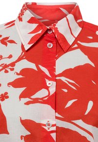 Camicia a bottoni rossa e bianca con motivi floreali, caratterizzata da colletto, grandi motivi a foglia e bottoni a contrasto su un tessuto morbido.