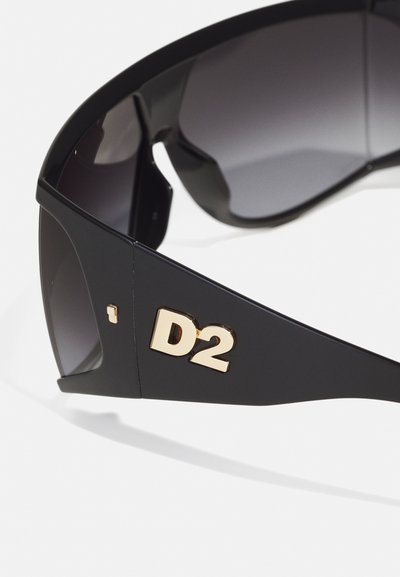 Crne sunčane naočale s sivim lećama. Imaju veliki zlatni „D2“ logo na djelu i elegantan dizajn okvira. Glatka tekstura i moderan oblik.