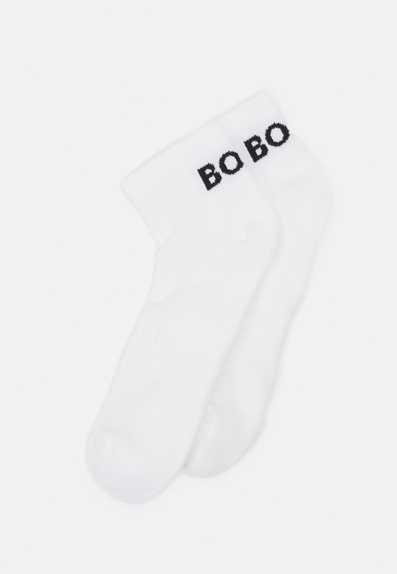 Vita bomullssockor med ribbad krage, med ordet "BOBO" i fet svart stil på sidan. Slät struktur och standardform.
