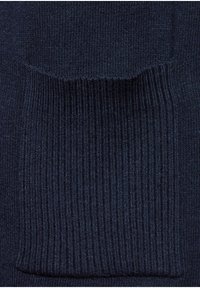 Tissu tricoté bleu foncé avec une poche rectangulaire côtelée cousue sur la surface.