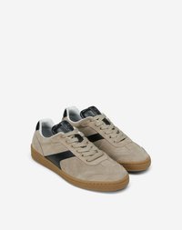 Baskets en suède beige avec des accents en cuir noir et une semelle en caoutchouc. Présentent un design à lacets et une bande noire contrastante sur le côté.