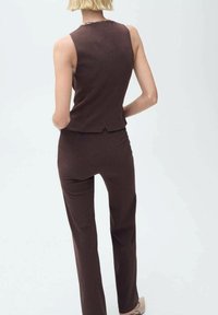 Haut sans manches marron et pantalon ajusté assorti, en tissu texturé, avec un design simple et un détail d'ouverture à l'arrière.