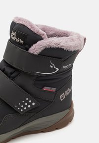 Czarne ocieplane zimowe buty z różowym sztucznym futrem, rzepem, teksturowanym akcentem i gumową podeszwą. Zawierają oznaczenie marki Jack Wolfskin.