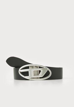 Cinto de couro preto com uma fivela oval prateada brilhante, apresentando um design geométrico. A correia é lisa, com uma extremidade afilada.