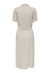 Belteklær av lin i lys beige, midi-lengde med korte ermer og krage med innsnitt. Baksiden har en subtil yoke-detalj.
