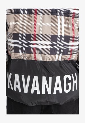 Pufferjakke med et beige, sort og rødt ternet mønster, sort nederste del med stor hvid tekst "KAVANAGH" i kanten.