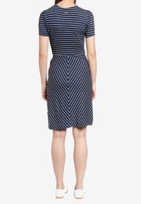 Vestito a righe navy con maniche corte, caratterizzato da linee orizzontali e verticali che formano un motivo a zigzag. Tessuto morbido, lunghezza al ginocchio.