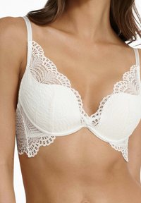 White lace bra with a plunging neckline, featuring floral patterns and scalloped edges. Adjustable straps and underwire for support.