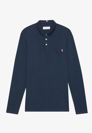 Polo de manga larga en color navy con cuello, tres botones y un bolsillo en el pecho que presenta un acento de rayas rojas y blancas. Material de algodón.
