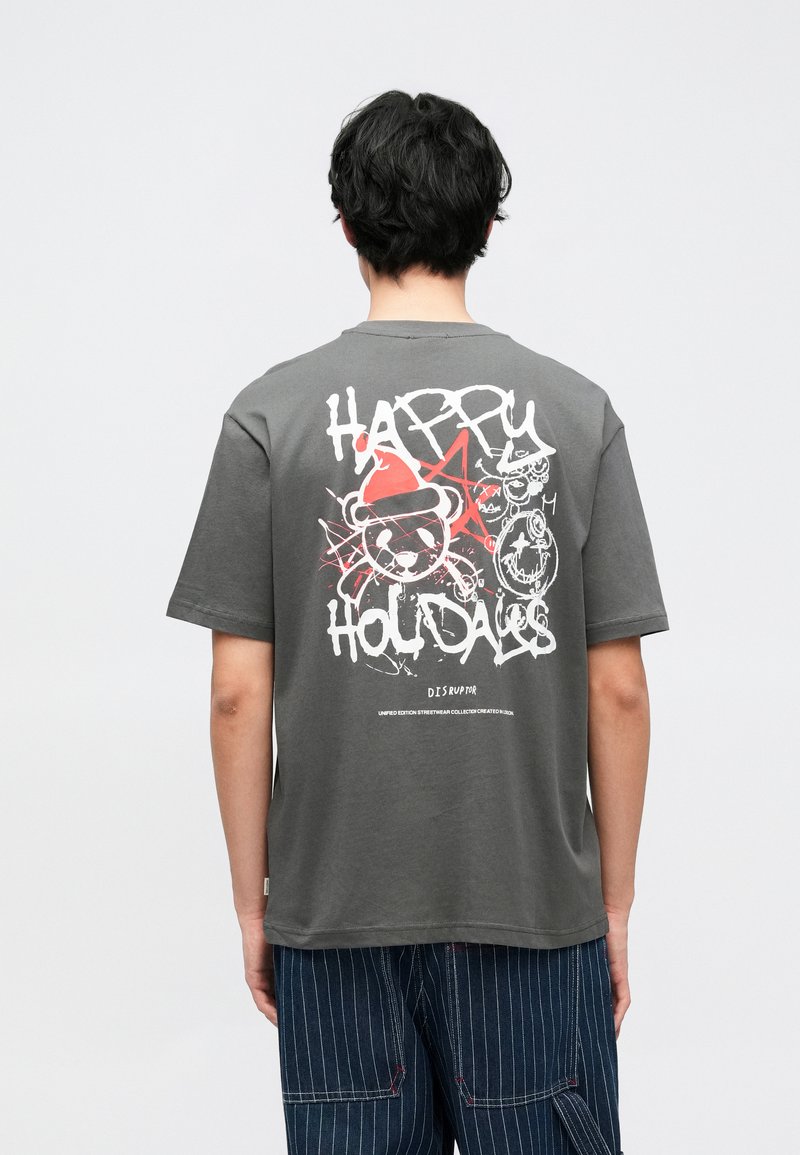 Siva pamučna majica kratkih rukava s okruglim izrezom, na leđima sadrži šareni grafički tisak koji uključuje tekst i crtane elemente.