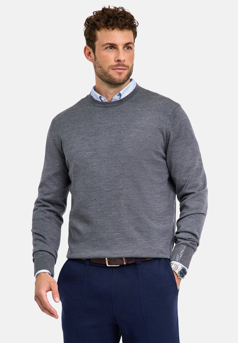 Maglione grigio a maglia con girocollo e maniche lunghe, indossato sopra una camicia azzurra a collo, abbinato a pantaloni blu scuro.