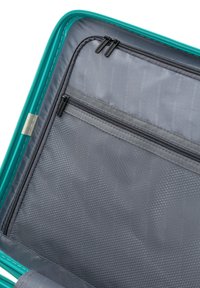 La valigia rigida in verde acqua presenta un interno in tessuto grigio con un motivo testurizzato, molteplici scomparti con cerniera e cuciture rinforzate.