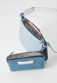 Denim shoulder bag in light blue with a detachable matching wallet. Both feature silver hardware and zip closures, lined with beige fabric.