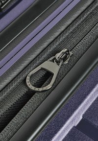 Maleta expandable con múltiples cremalleras en negro y púrpura, con un tejido texturizado y elegantes acentos de hardware mate.