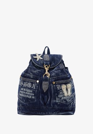 Denim-reppu, jossa on pyöreä läppä, hopeanvärisiä niittejä ja koristeellisia yksityiskohtia. Siinä on taskuja, joissa on kirjontaa ja kristallimeritähti.