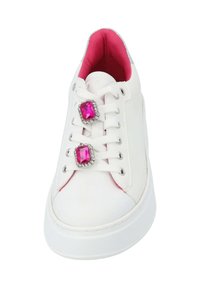 Zapatilla blanca con una superficie lisa, acentos rosas en el interior y dos prominentes decoraciones de gemas falsas en los cordones. Suela de goma, costuras mínimas.