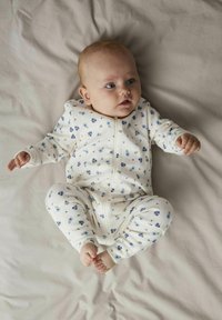 Vit babydräkt med blommönster, prydd med små blå och gröna blommor. Den har en framdragkedja och långa ärmar.