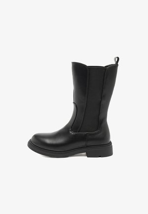 Stivaletto nero alla caviglia con finitura in pelle liscia, pannello laterale elastico e suola bassa in gomma testurizzata. Presenta una maniglia ad anello sul retro.