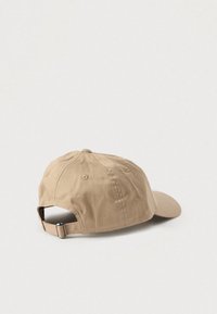 Șapcă de baseball din pânză de culoare bej, cu vizieră curbată, curea ajustabilă în spate și orificii de ventilație pe partea superioară. Textură moale.