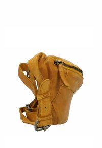 Borsa in pelle color tan con forma arrotondata, chiusura a zip, tracolla regolabile e dettagli di cucitura. La texture appare liscia e leggermente invecchiata.