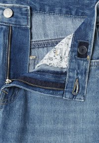 Jeans de mezclilla con cierre de cremallera y botón, en un lavado azul medio con costuras visibles y un detalle de tela estampada en el interior de la cinturilla.