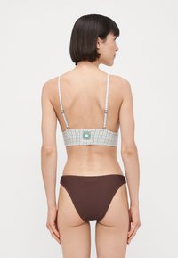 Večbarvna karirana zgornji del bikinija z tankimi naramnicami in okrasnim logotipom, v kombinaciji z enobarvnimi rjavimi rebrastimi spodnjim delom bikinija.