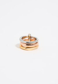 Stacked ring set featuring three bands: silver, rose gold, and gold; smooth textures with varying heights and shapes, creating an interlocking design.