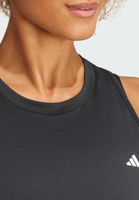 Zwarte sportieve tanktop met een ronde halslijn en subtiele textuur. Kenmerkt zich door een klein wit logo aan de linkerkant. Gladde stofafwerking.