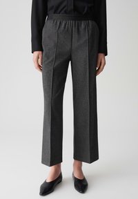 Grijze op maat gemaakte broeken met een textuurpatroon, wide-leg ontwerp, elastische tailleband en een paar zwarte instap schoenen.
