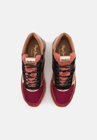 Baskets combinant des matériaux rose, bordeaux et noir. Forme arrondie, surfaces texturées, lacets et détail de semelle intérieure avec logo.