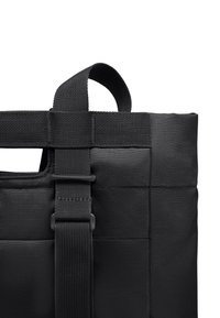 Zwarte tote bag met een gestructureerd oppervlak, voorzien van een bovenhandgreep en een verstelbare webbing schouderriem voor het dragen. Vierkante vorm met versterkte naden.