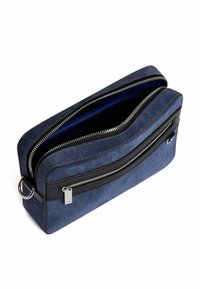 Borsa a tracolla in denim con esterno in tessuto blu, dettagli in pelle nera, due scomparti con zip e un particolare in metallo argentato.