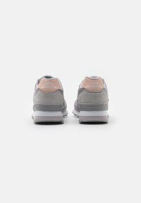 Gray suede and mesh New Balance sneakers with a light pink accent on the heel and white sole, showcasing a rounded, sporty design.