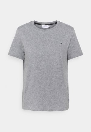 Šedé bavlněné tričko s krátkými rukávy, kulatým výstřihem a malým černým logem na levé hrudi. Jednoduchý a nenápadný design.