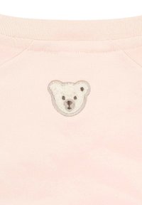 Sudadera rosa con un parche bordado de una cara de oso redonda en blanco y gris, que presenta contrastes de textura y un escote curvado.