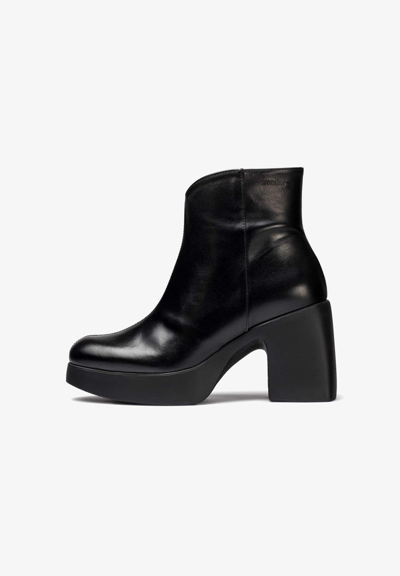Botín negro de cuero hasta el tobillo con una textura suave, punta redondeada y un tacón de plataforma grueso. Presenta un marcado mínimo en relieve en un lado.