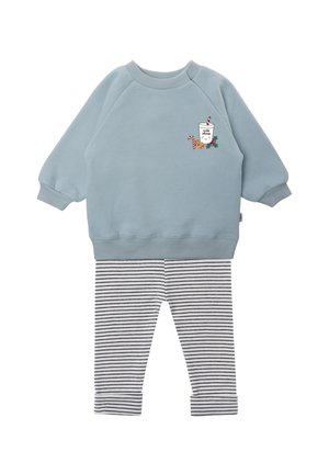 Hellblauer Pullover mit einem grafischen Design, das ein Getränk und Zuckerstangen zeigt, kombiniert mit schwarz-weiß gestreiften Leggings. Weiches Material.