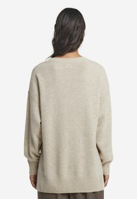 Beige Übergröße Pullover mit Rundhals, gerippten Bündchen und Saum, weicher Textur und überschnittenen Schultern. Schlichte Gestaltung, keine Muster oder Akzente.