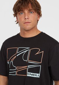 Sort bomulds t-shirt med et stort, abstrakt design i lys blå og koral, med en tekstureret grafisk print og korte ærmer.