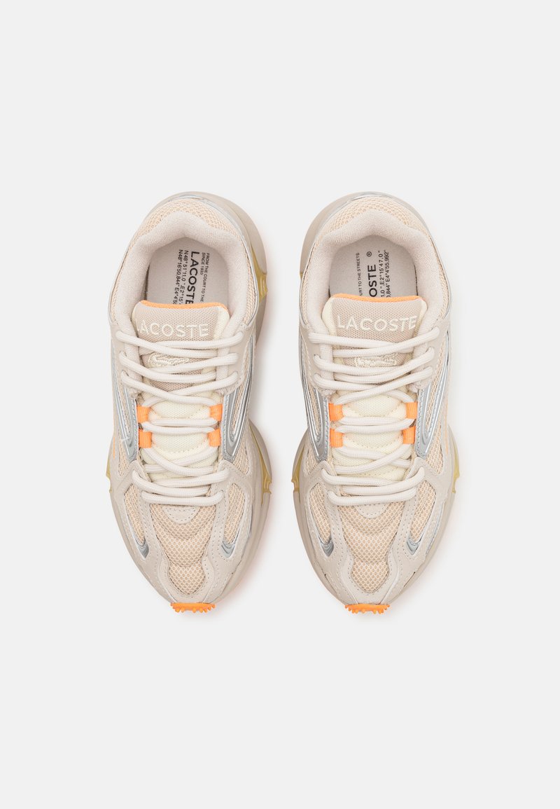Zapatillas deportivas beige con superposiciones de malla y sintéticas, que presentan detalles en gris, toques naranjas en los cordones y una suela texturizada.