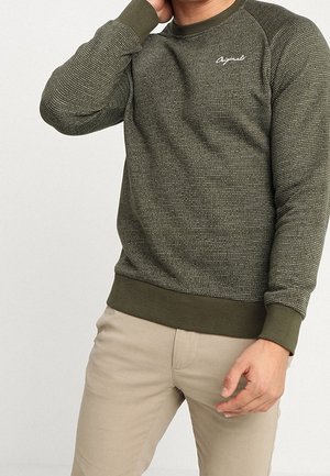Olijfgroene sweatshirt met gestructureerde stof, raglanmouwen en een geribde kraag en zoom. Bevat een klein wit logo op de borst.