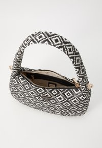 Sac à main à motifs noir et blanc avec une bandoulière tressée, fermeture éclair et détail de logo doré. Dispose d'une poche intérieure zippée.