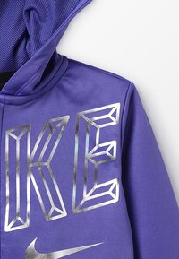 Fioletowy hoodie Nike z meshowym kapturem, ozdobiony dużym, srebrnym, trójwymiarowym napisem "NIKE" oraz srebrnym logo swoosh.