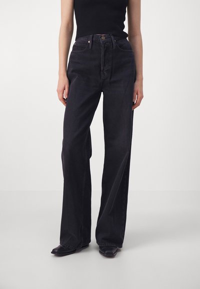 Jean en denim délavé foncé avec taille haute, coupe évasée, coutures visibles et fermeture à bouton classique. Texture lisse, sans motifs ni ornements.