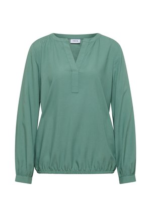 Grön blus med V-ringning och lång ärm. Har en rynkad midja och elastiska manschetter, tillverkad av ett jämnt, lätt tyg.