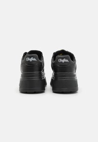Black sneakers with a smooth leather upper, thick sole, and padded collar. Features embossed logo on the back and textured rubber accents.