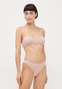 Light pink ribbed crop top with thin straps and matching bikini bottom featuring a soft texture and subtle logo detail.