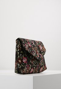 Bolso de mano con patrón floral sobre un fondo negro, con detalles en rosa y tonos joya, hecho de tela texturizada con un cierre de solapa triangular.