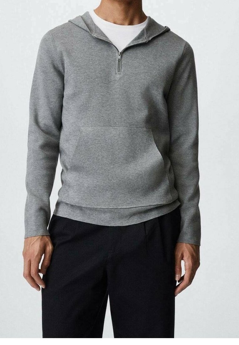 Un sweat à capuche gris zippé avec une poche avant, fabriqué en tissu doux, comporte une capuche, des manches longues et une coupe décontractée. Associé à un pantalon noir.